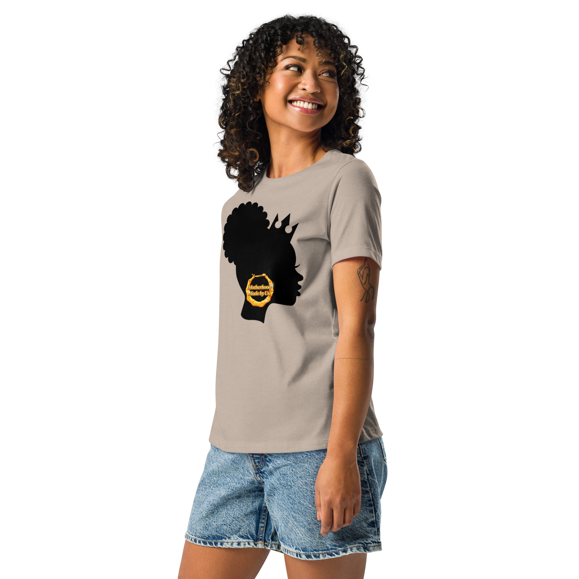 A smiling person wears a beige t-shirt featuring a graphic design of a woman with an afro and a yellow accessory.